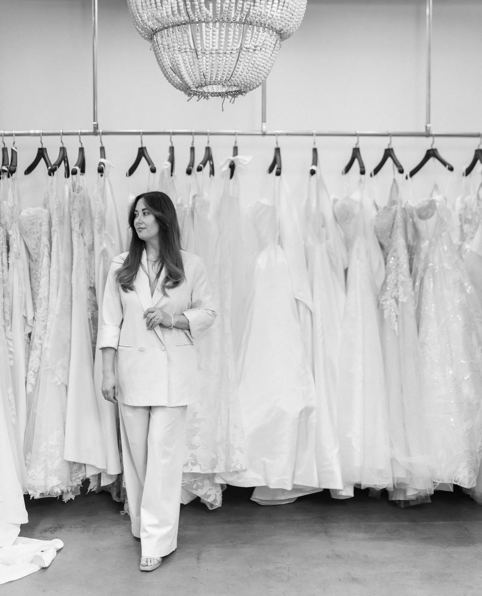Adriana Garcia standing under the chandelier on the shop floor at Cande Bridal Boutique