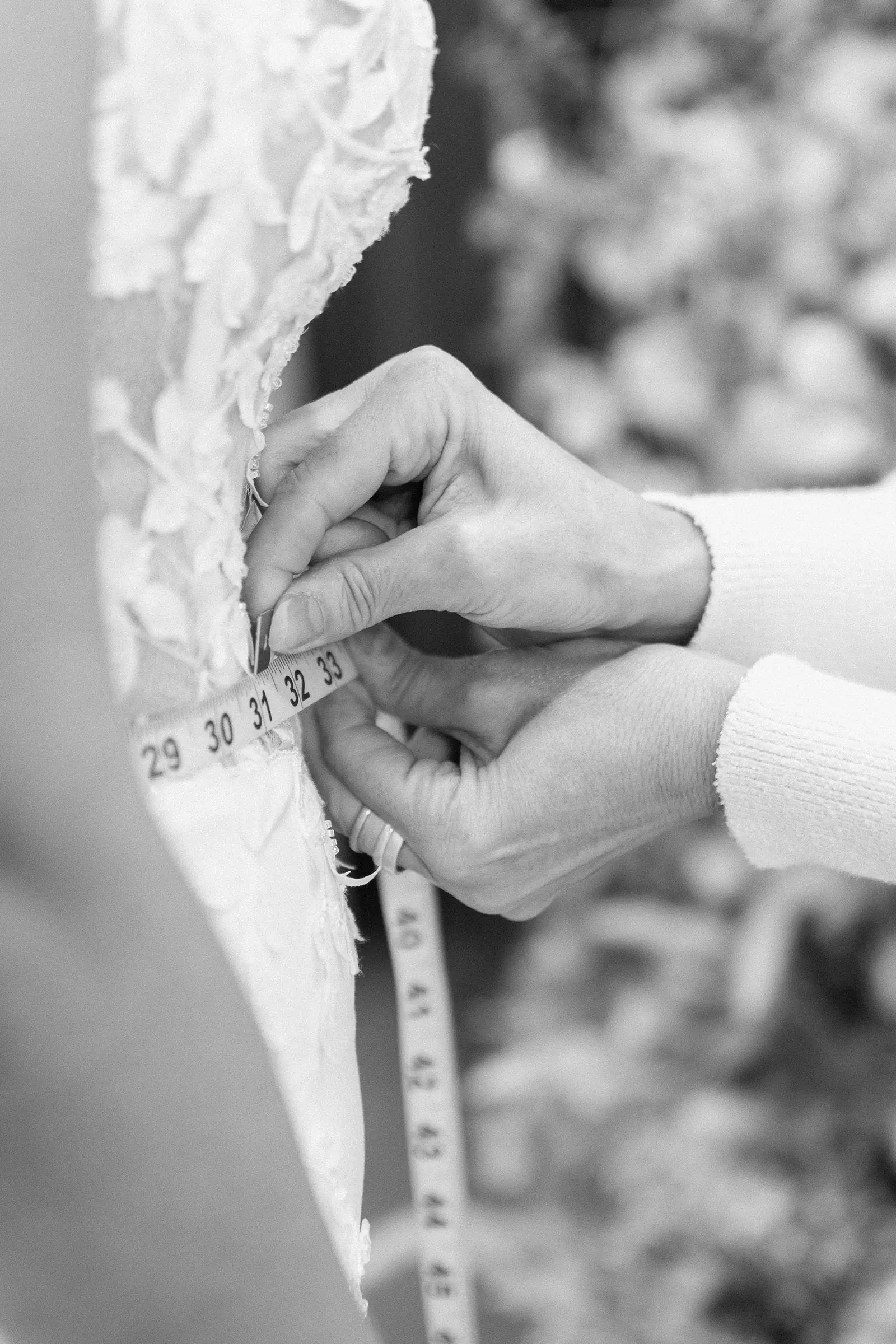 A seamstress taking a measurement over the bodice of a wedding gown in the workroom at Cande Bridal Boutique in Kelowna, British Columbia