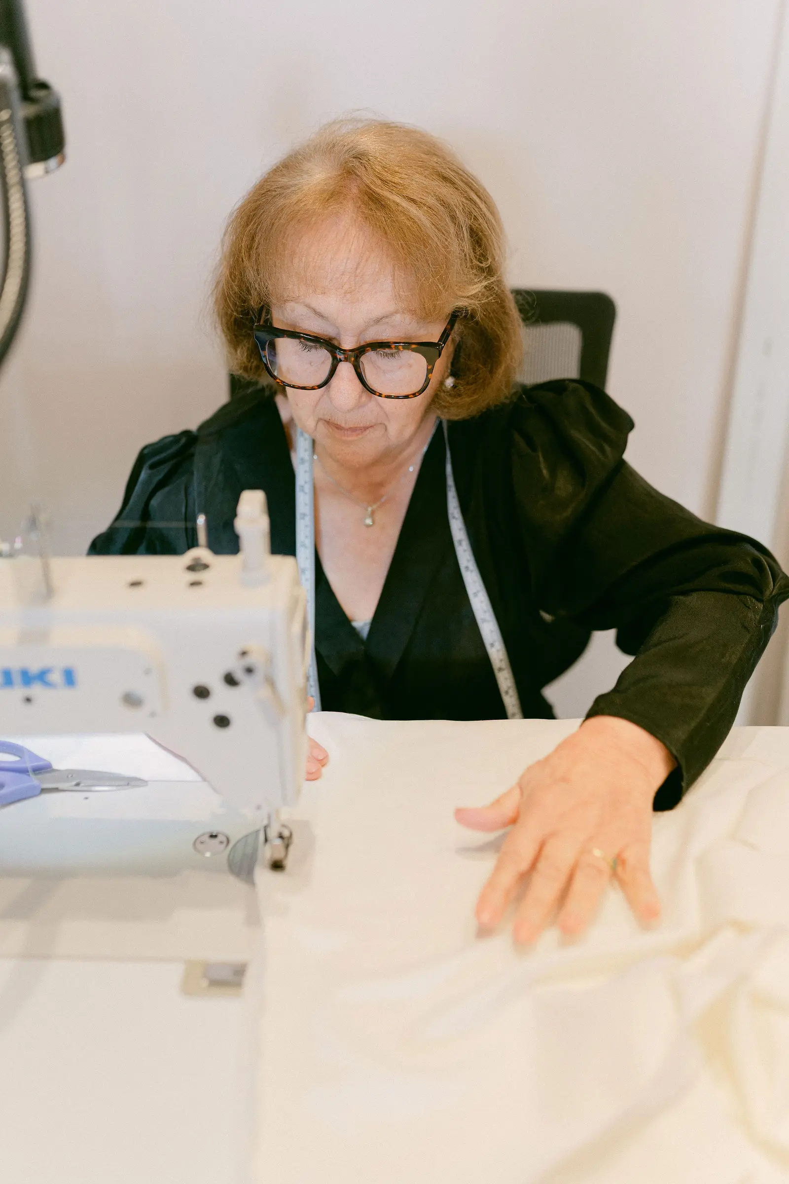 A seamstress sewing a wedding gown in the alterations workroom at Cande Bridal Boutique